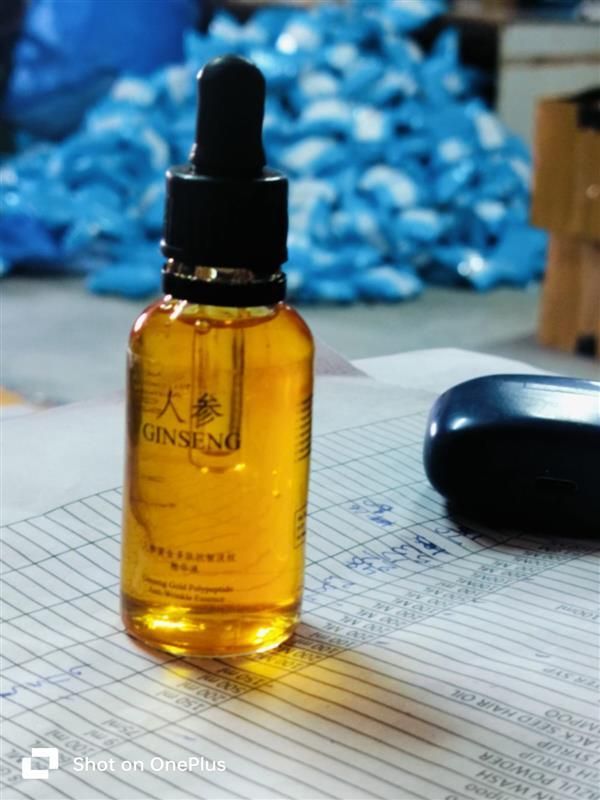 Bottle of Ginseng extract on a table with blue flowers in the background